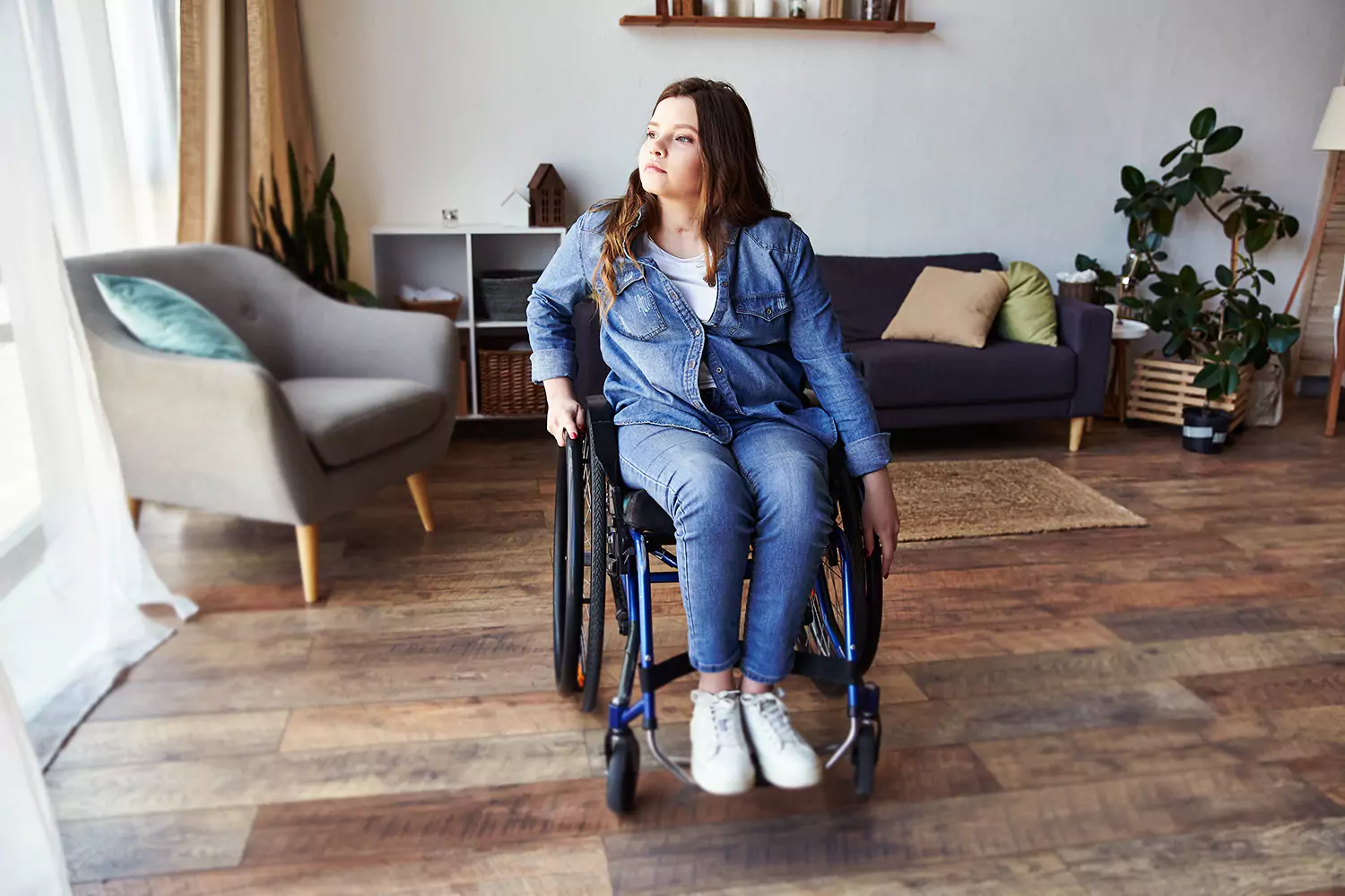 A physically disabled woman in a wheelchair is sitting in her living room