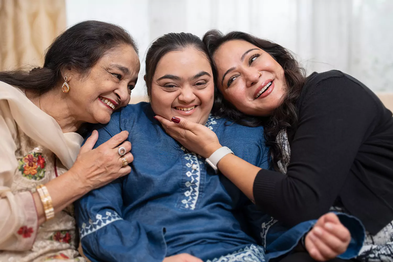 A down syndrome woman is smiling and hugging her family while indoors